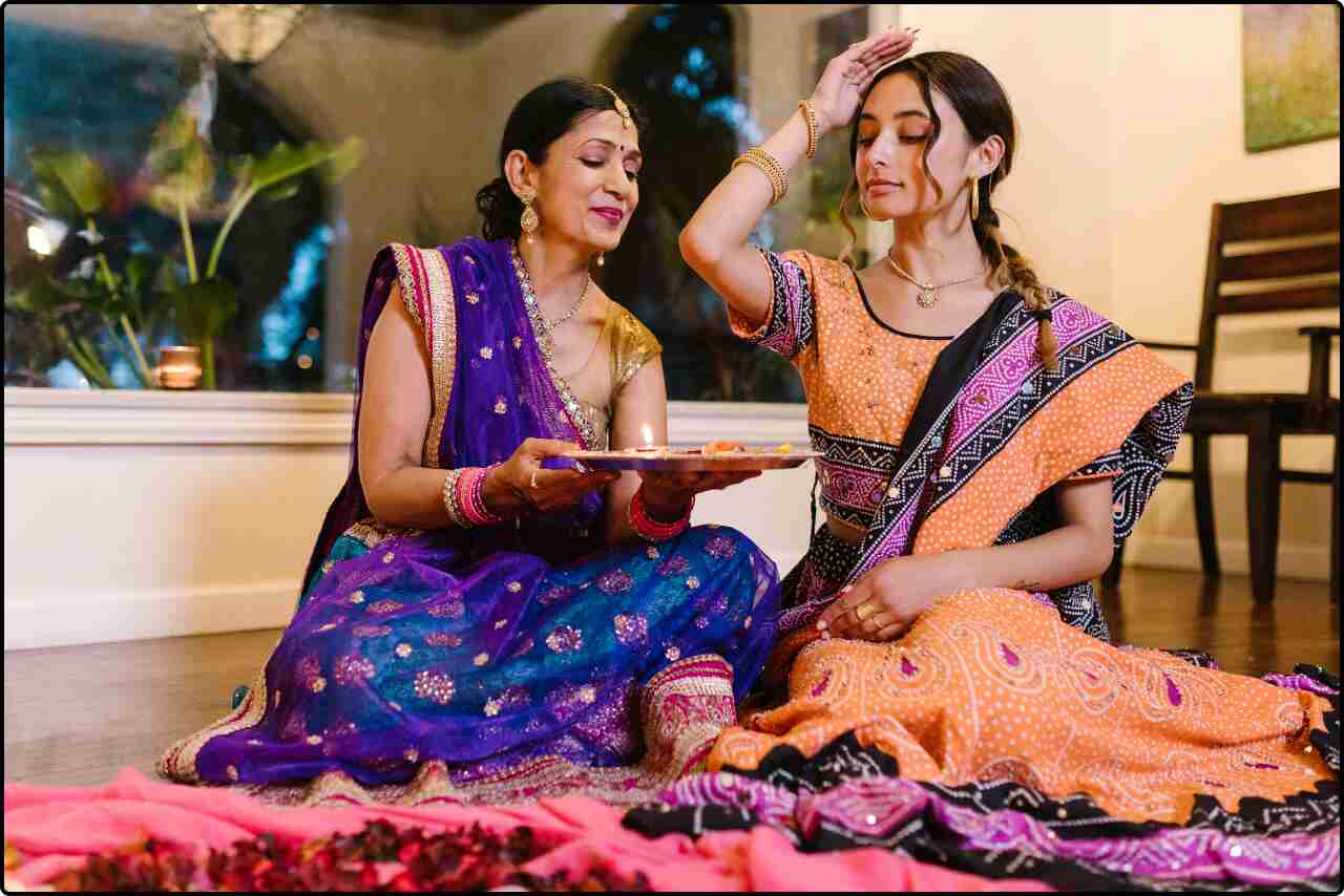 Women holding a beautifully decorated Puja Thali with diyas and flowers for Diwali